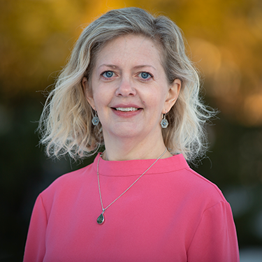 Charlotte Andersson in a pink shirt in front of a blurred background