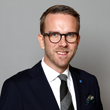 andreas carlsson in a suit in front of a grey bsackground