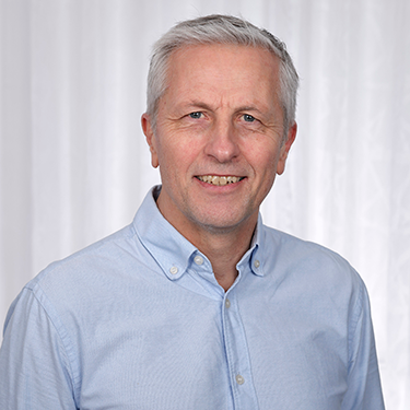 Magnus Ahlström in a blue shirt in front of a light grey background