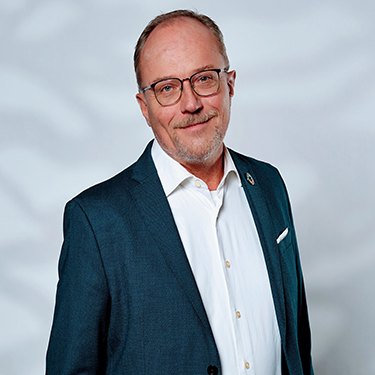 Martin Svensson in a suit, in front of a light great background.