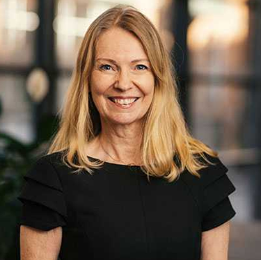 Agneta Jacobson standing in a black top in front of a window with light coming in