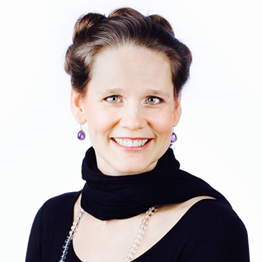 Marit Finch Westin smiling in a semi closeup in front of a white background