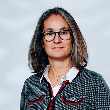 Verena Adamheit standing in front of a grey background (semi close up)